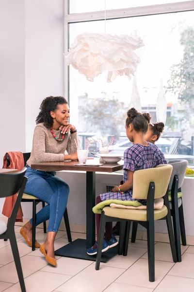 Hermosa madre elegante mirando a sus chicas lindas sentadas en la cafetería — Foto de Stock