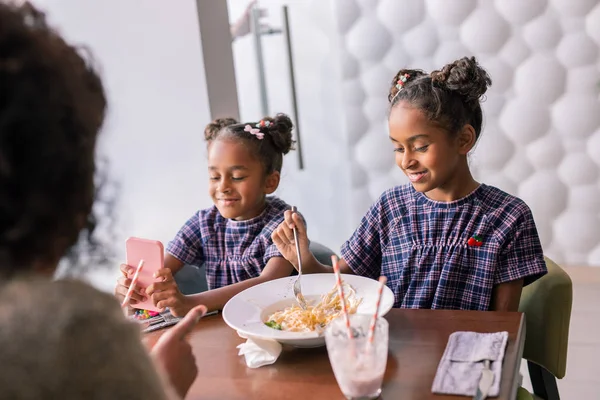 Dos hijas se sienten emocionadas mientras comen en la cafetería con la madre — Foto de Stock