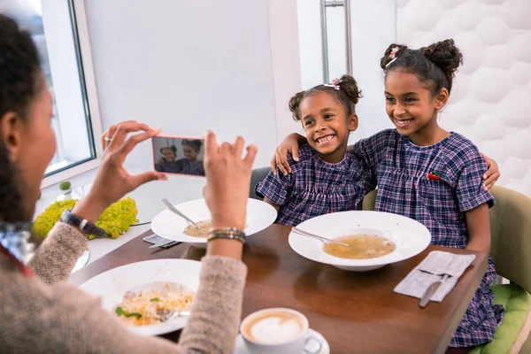 Madre sosteniendo teléfono inteligente haciendo foto de sus hijas elegantes lindo —  Fotos de Stock