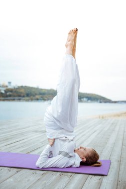 Onu sabah egzersizleri bir parçası olarak desteklenen Shoulderstand yapıyor kadın