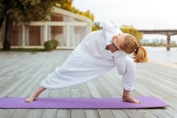 Yogi dehnt ihre Muskeln, während sie Übungen macht — Stockfoto