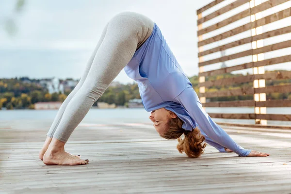 Mujer que practica de forma concentrada la pose de yoga del perro boca abajo — Foto de Stock