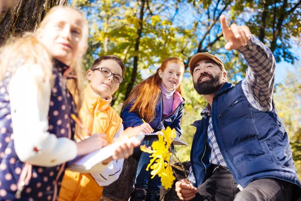 Alegre hombre barbudo inteligente mostrando el bosque de otoño — Foto de Stock