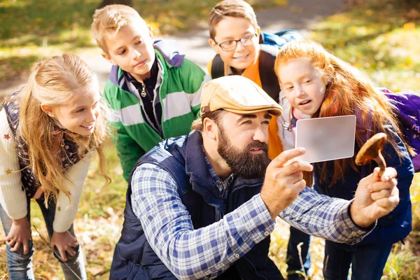 Bir mantar elinde tutan ciddi sakallı adam