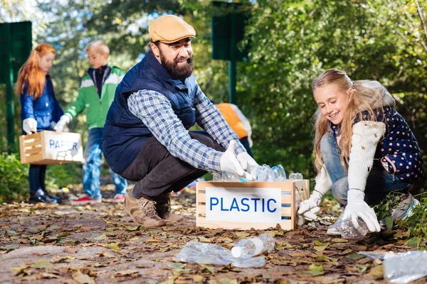 Chica linda positiva recogiendo botellas de plástico en el parque — Foto de Stock