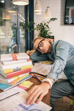 Bilgi edinme. Kitaplar tarafından çevrili ise masadan ciddi genç öğrenci