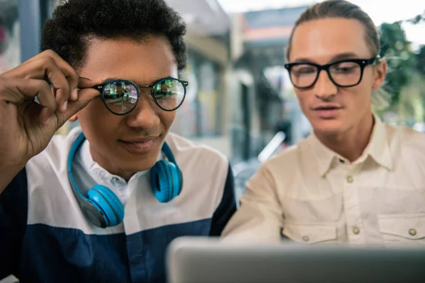 Nice young men sitting together at the laptop