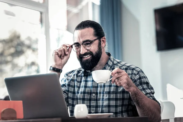 Bearded man wearing glasses having video chat with his old friend