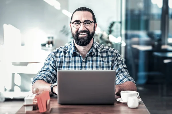 Hombre barbudo alegre con gafas sonriendo después de un día exitoso — Foto de Stock