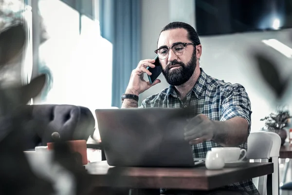 Escritor independiente de cabello oscuro llamando a su colega trabajando remotamente — Foto de Stock