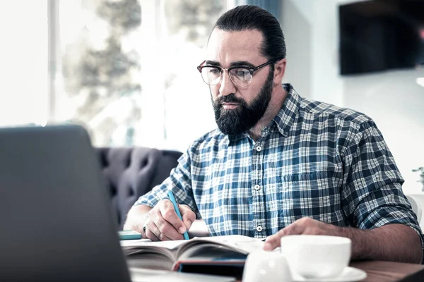 Skäggig mörkögda man känsla som koncentreras till att arbeta med artikel — Stockfoto