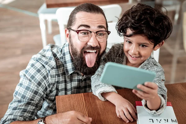 Lindo hijo pequeño sosteniendo teléfono haciendo foto con su padre —  Fotos de Stock