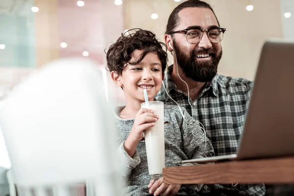 Χαριτωμένος όμορφος γιος πόσιμο milkshake και κάθεται κοντά τον πατέρα του — Φωτογραφία Αρχείου