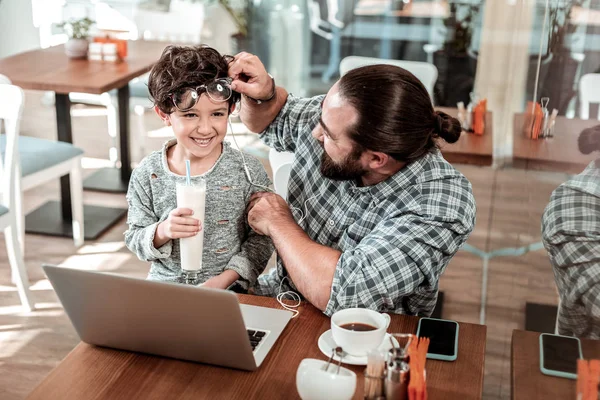 Lindo hijo de pelo oscuro riendo mientras se divierte con su padre cariñoso — Foto de Stock