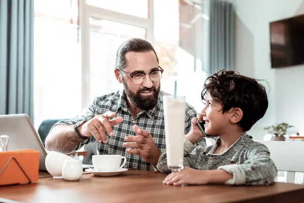 Γενειοφόρος μελαχρινός πατέρα φορώντας γυαλιά μιλάμε για χαριτωμένο μικρό γιο του — Φωτογραφία Αρχείου