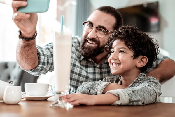 Happy father holding blue smartphone making selfie with son — Stock Photo, Image