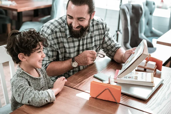 Feliz hijo moreno riendo sintiéndose increíble estudiando con papá — Foto de Stock