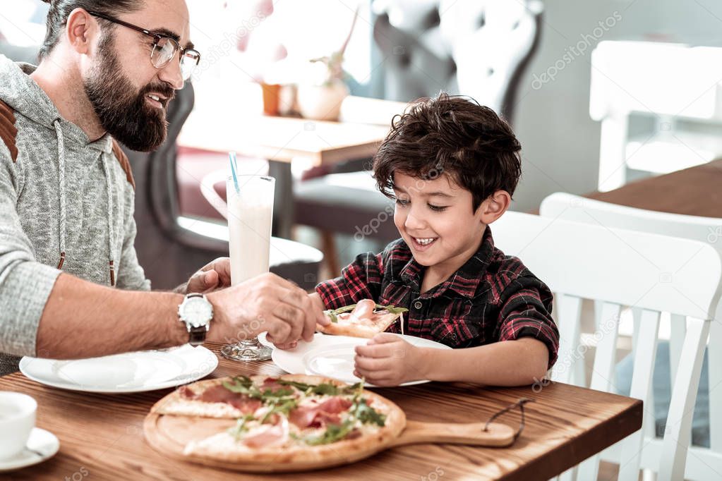 Father and son having tasty pizza for lunch on weekend
