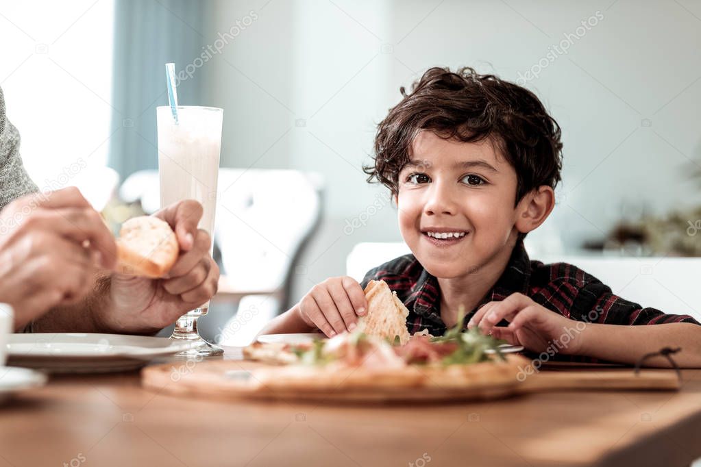 Bearded dark-haired father eating pizza with his younger son