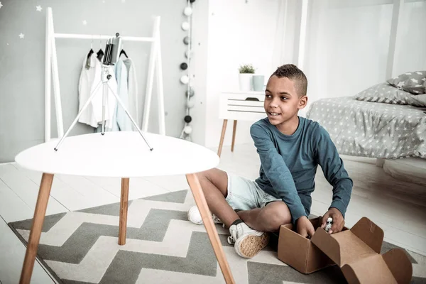 Vrolijke positieve jongen zittend op de vloer — Stockfoto