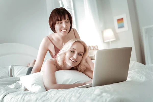 Blonde smiling woman lying in the bad with partner