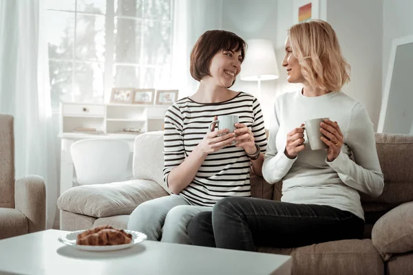 Kvinnliga vänner att ha varma drycker och croissanter till frukost — Stockfoto