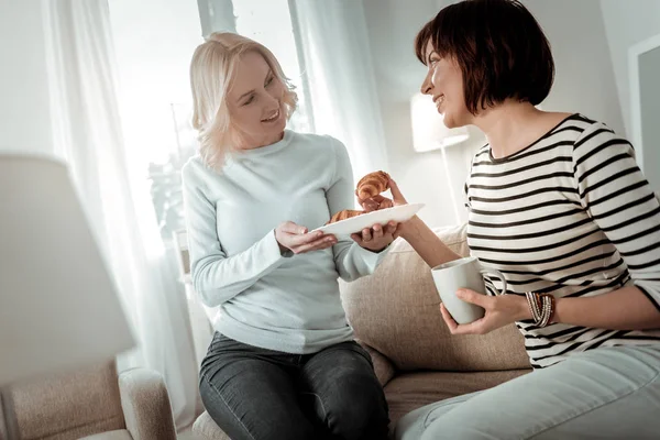 Impresionante pareja comiendo croissants de un plato — Foto de Stock