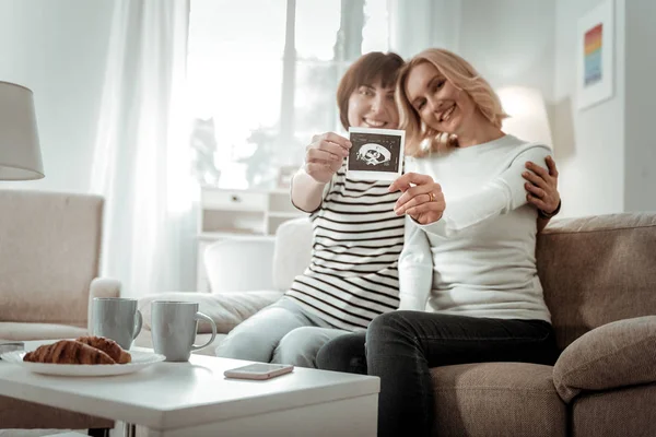 Future mothers holding photo from ultrasound procedure