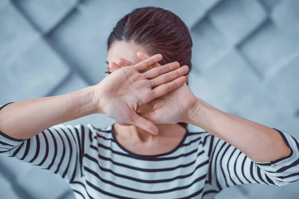 Ung kvinna täcker hennes ansikte med korsade händer — Stockfoto