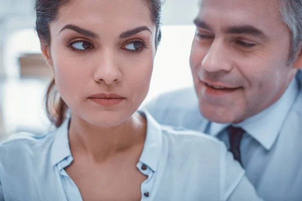 Unpleasant man whispering in ear of his female coworker