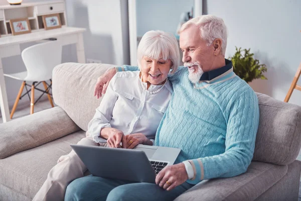 Счастливая пожилая пара смотрит фотографии на ноутбуке — стоковое фото