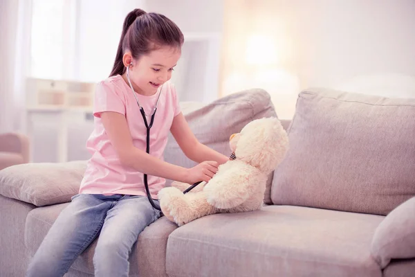 Linda niña fingiendo ser médico jugando con su osito de peluche — Foto de Stock