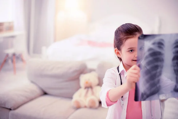 Little preschool girl pretending to be a doctor looking at x-ray of her mom