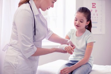 Koyu renk saçlı küçük kız geliyor doktora kolunu kırma sonra