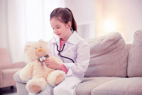 Little preschool girl wearing white jacket playing in doctor games — Stock Photo, Image