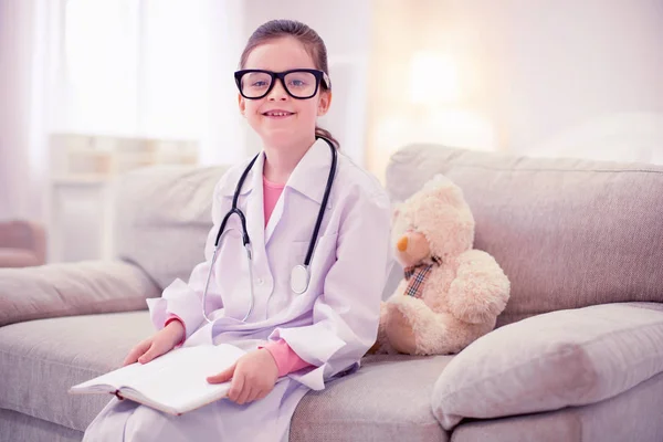 Flicka som bär glasögon och vit jacka att ha en önskan att bli läkare — Stockfoto