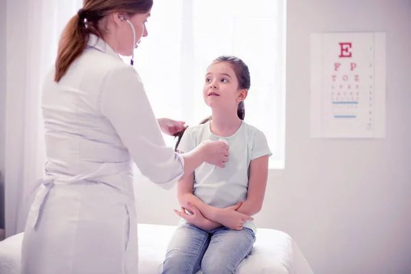 Family physician listening to lungs of little cute girl feeling sick