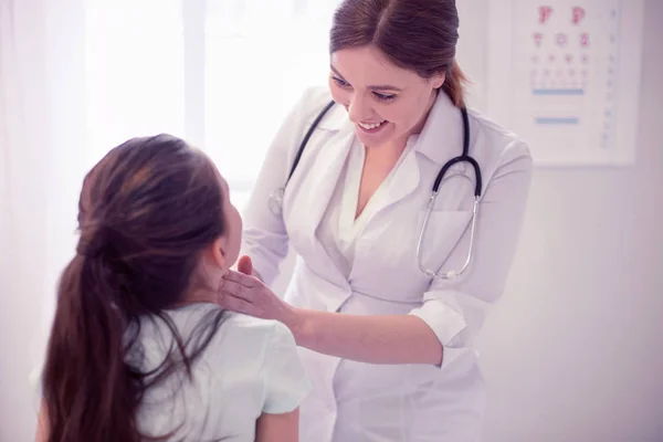 Усміхнений дбайливий сімейний лікар досліджує горло маленької дівчинки — стокове фото