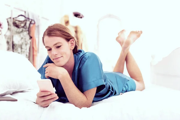 Sorrindo bonito sexo-queer refrigeração na cama enquanto mensagens de texto — Fotografia de Stock