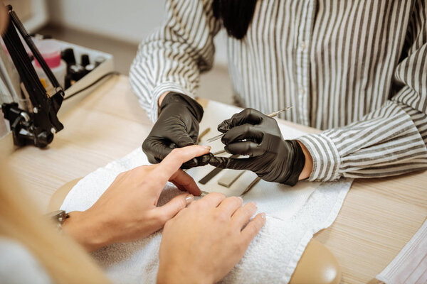 Professional manicure master removing cuticle of her client
