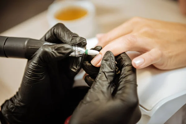 Крупный план мастера маникюра в черных перчатках полировки ногтей — стоковое фото