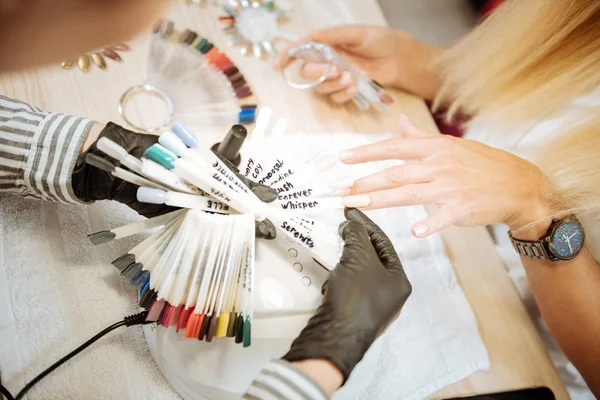 Experienced nail artist wearing black gloves choosing the best color