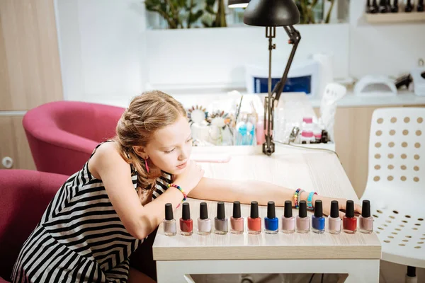 Het dragen van gestreepte meisjeskleding kijken naar kleuren van nagellak — Stockfoto