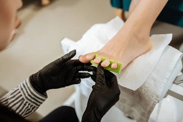 Professioneller Fußpfleger mit gestreifter Bluse, der hart arbeitet — Stockfoto