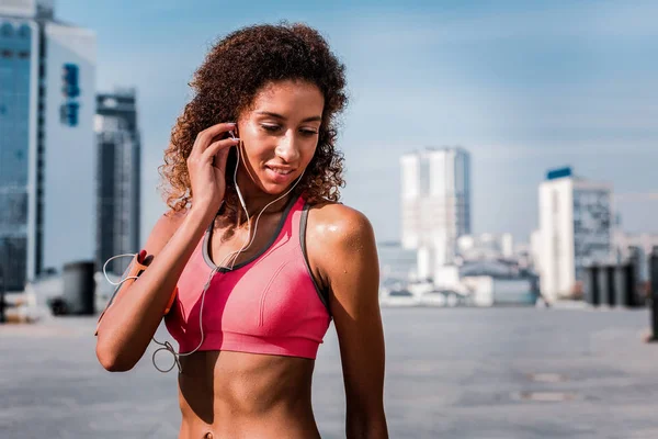 Mujer atractiva y alegre escuchando música durante su entrenamiento — Foto de Stock