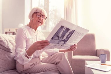 Meraklı yaşlı kadın dikkatle ilginç bir gazete okuma
