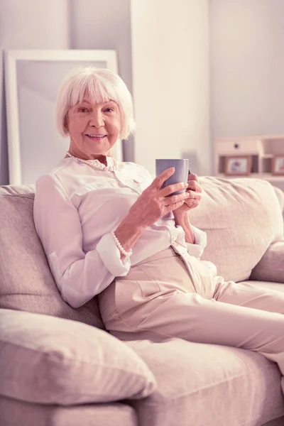 Vieja sonriente sentada con una taza de café — Foto de Stock