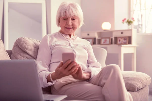 Mulher mais velha bonita entusiasticamente monitorando seu telefone — Fotografia de Stock