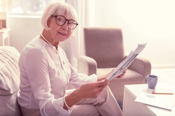 Smiling positive senior woman carrying fresh newspaper — Stock Photo, Image