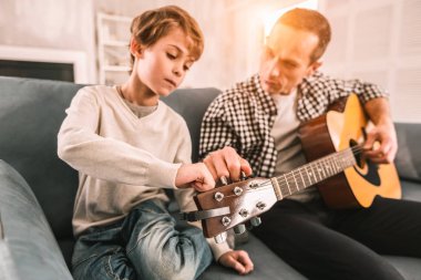Yaratıcı yetişkin meraklı çocuğunu gitar inceliklerini öğretme.